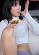 A woman sitting on a couch eating a donut.