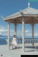 A woman sitting on a bench under a gazebo on the beach.